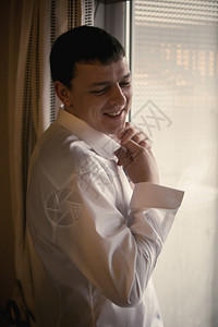 身穿白衬衫的窗边微笑优雅男子的画像图片