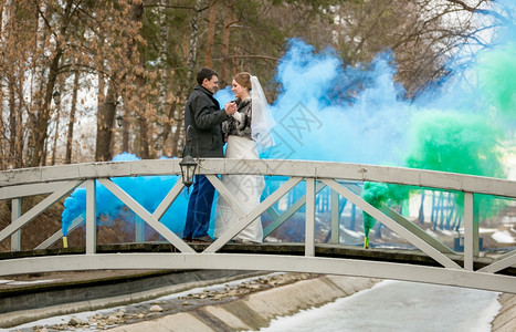 蓝烟和绿色雾覆盖新婚夫妇在森林桥上跳舞图片