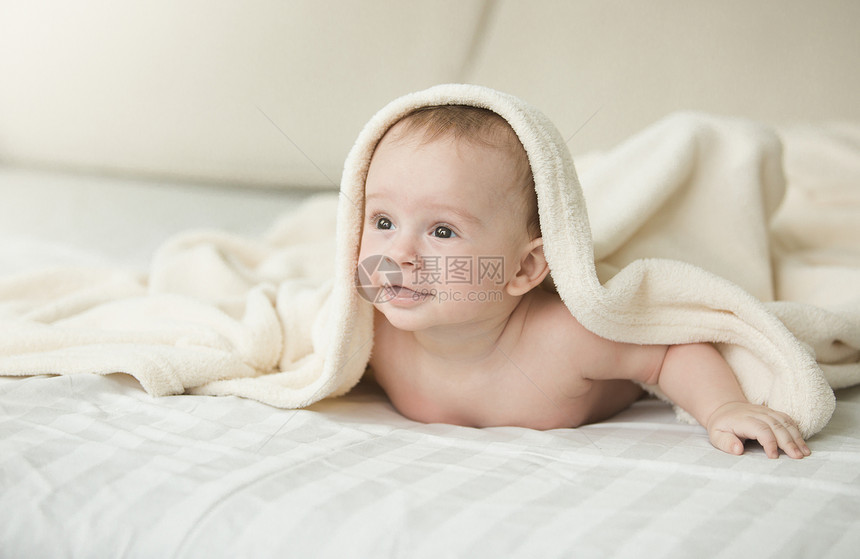 躺在床上的毯子下可爱快乐婴儿肖像图片