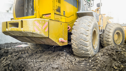大黄色推土机在地面工作时被泥土覆盖背景图片