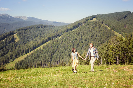 一对旅行的夫妇在夏季草地一起走来去环望山景图片