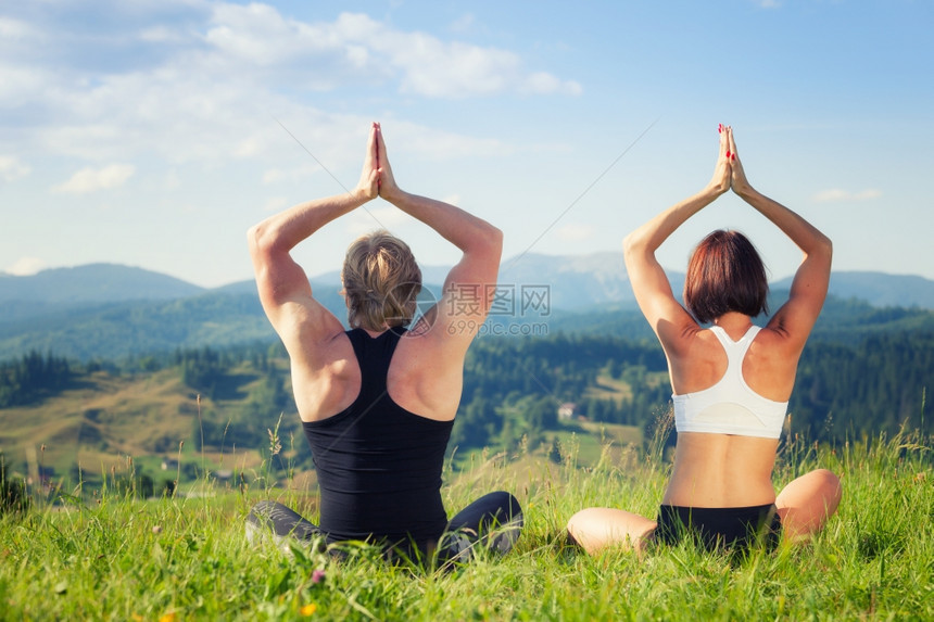 美丽的青年男女在夏季草原上做瑜伽锻炼图片