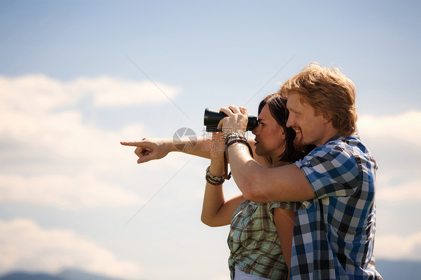 年轻旅行者夫妇透过望远镜寻找图片