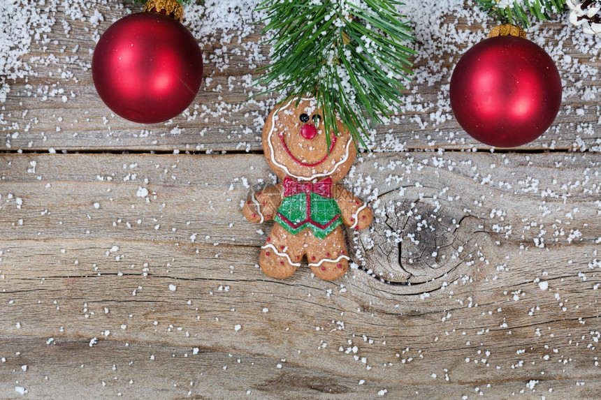 紧贴圣诞姜饼干红色装饰品和雪卷枝在生锈的木头上图片