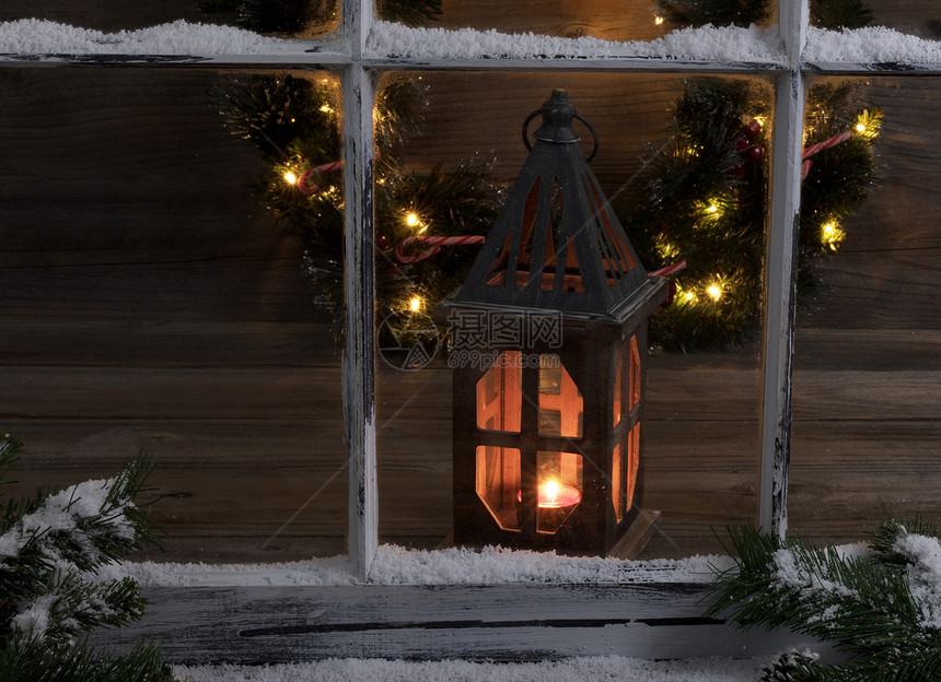 看见有灯笼和圣诞花圈透过雪窗遮盖着圆形树枝的灯笼和圣诞花圈图片