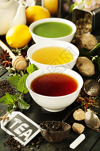 茶叶概念陶瓷碗中不同种类的茶叶和木制背景材料图片