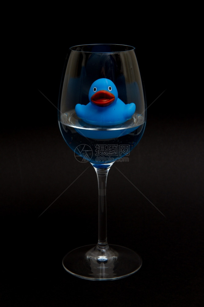 有水黑色背景的玻璃中的蓝橡胶鸭图片
