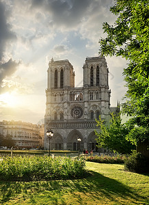 云哥特式巴黎圣母院和日出时绿草地法国背景
