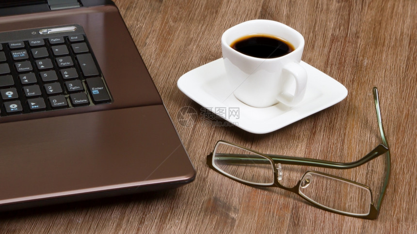 用笔记本电脑在木地板上戴眼镜的埃斯法咖啡图片