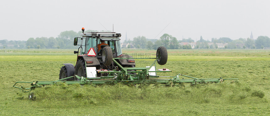 农民用拖拉机在干燥的田地上撒草图片