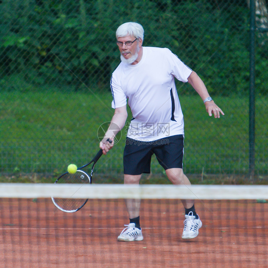 在碎石场打网球的年长男子图片
