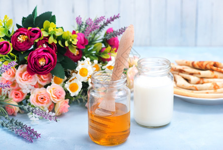 鲜花背景的牛奶和蜂蜜图片