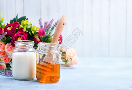 鲜花背景的牛奶和蜂蜜背景图片