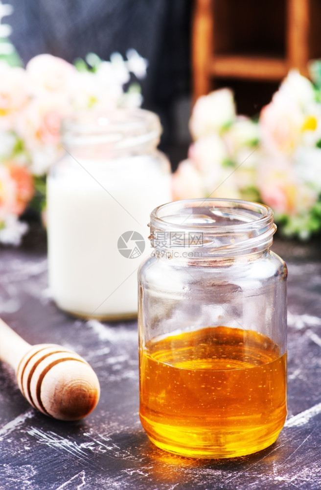 鲜花背景的牛奶和蜂蜜图片
