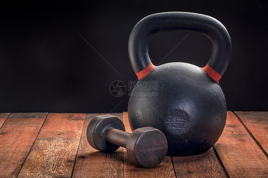 锻炼体重木制生锈甲板上的重铁电铃和哑家庭健身房概念图片