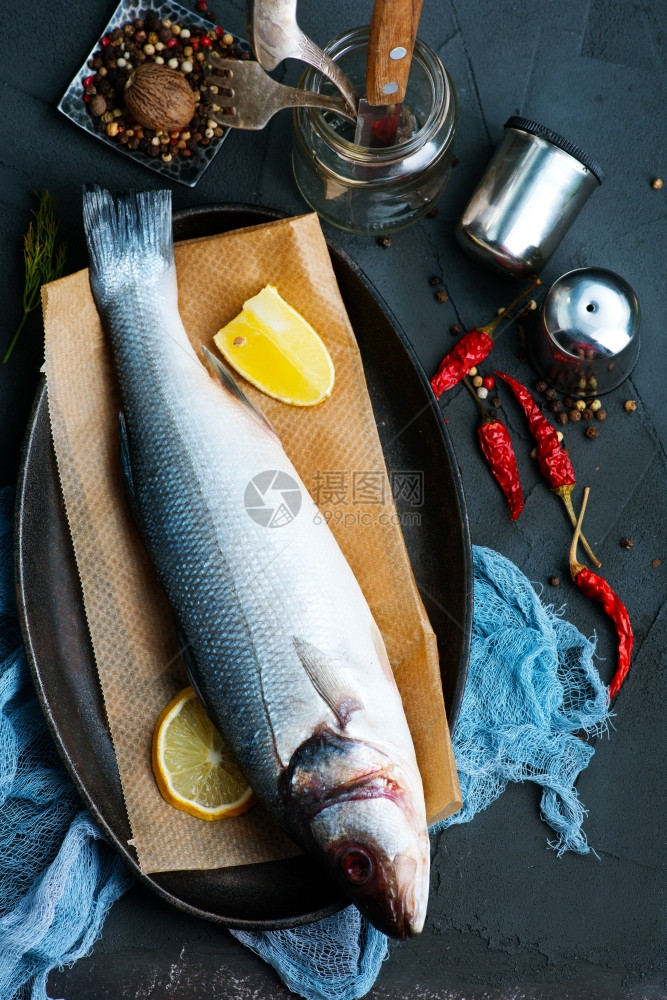 餐桌上加柠檬和香味料的生鱼图片