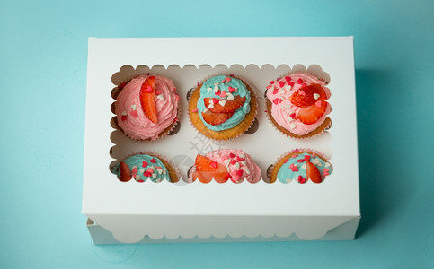 6个彩色纸杯蛋糕装满喷水和草莓的彩色纸杯放在封闭盒里图片