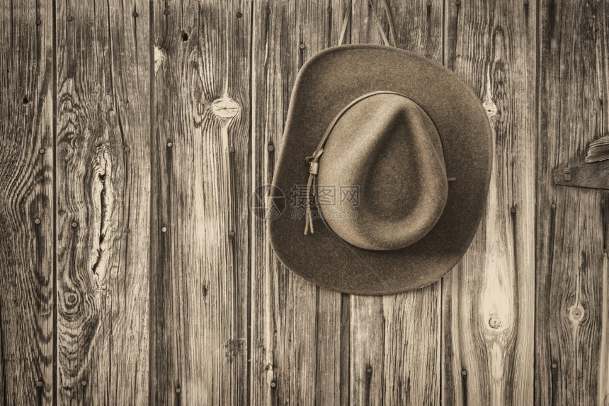 黑白黑的古老谷仓木墙上挂着皮头巾的牛仔帽图片