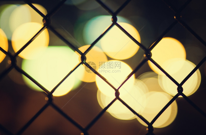 附近城市的灯光穿过铁丝网栅栏图片