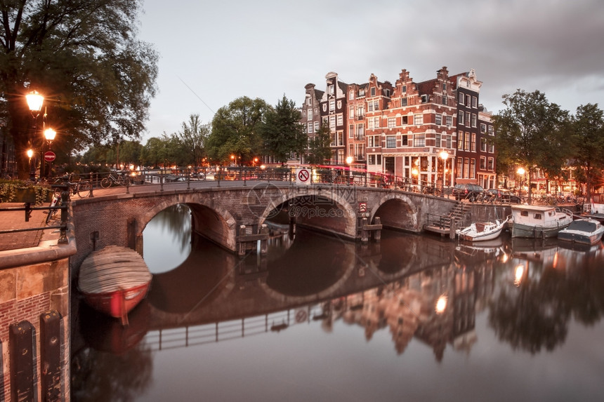 阿姆斯特丹运河和桥梁的夜间城市景色阿姆斯特丹运河桥梁和典型的房屋船只和自行车晚上清晨蓝色时荷兰图片