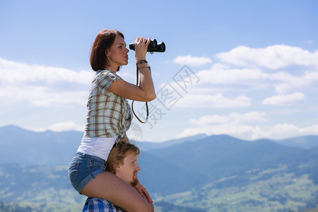 年轻旅行者夫妇透过望远镜寻找图片