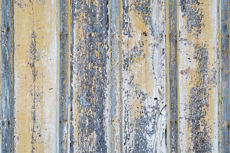 生锈和风化的木材背景废弃房屋墙上的木板涂有蓝色和黄的涂料图片