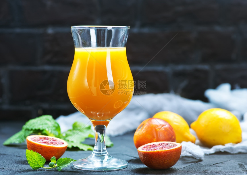 新鲜橙子和果汁在桌上的玻璃杯中图片