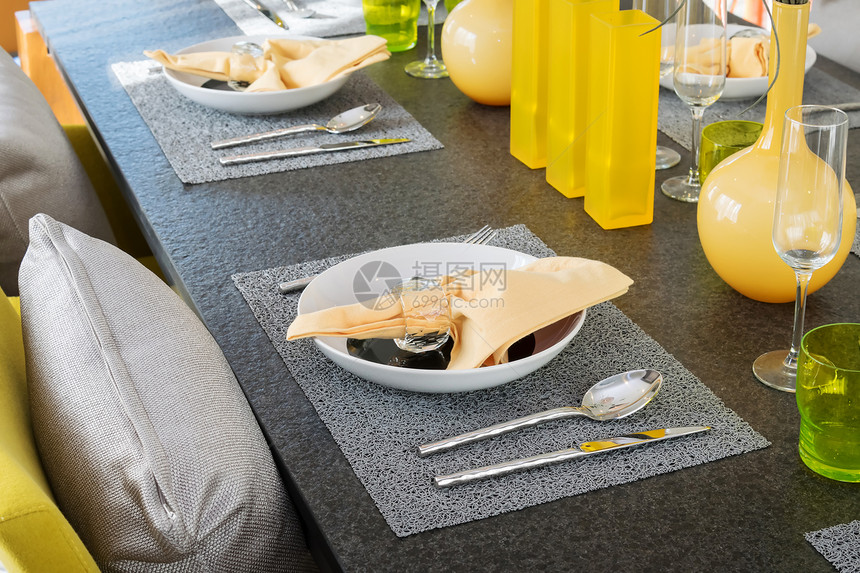 餐桌上用黄色和灰的装饰板摆着一张盘子图片