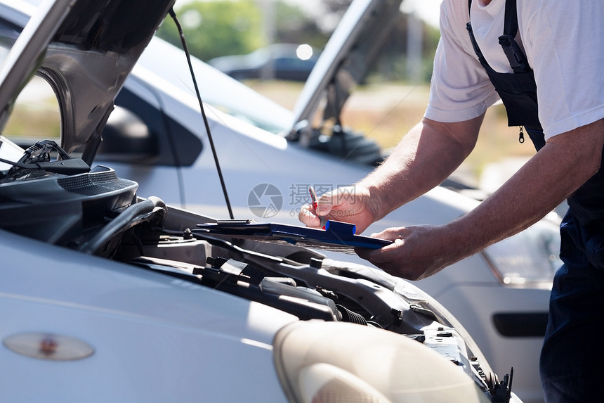 汽车或机械师检查发动机并在剪贴板上写字图片