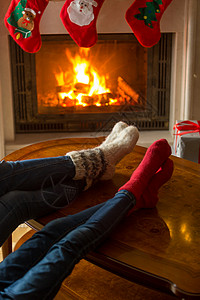 家庭穿针织的羊毛袜子在家里燃烧的壁炉暖图片