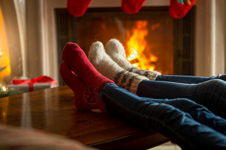 在起居室燃烧的壁炉附近暖羊绒袜子家庭脚图片