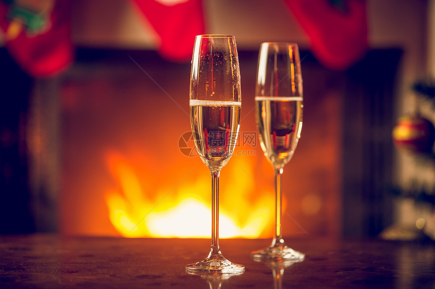 在壁炉前的圣诞桌上两杯子的香槟图片
