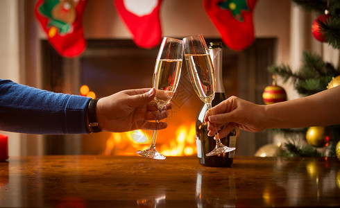 男人和女一起吃圣诞晚餐和紧贴着玻璃杯的火炉边图片