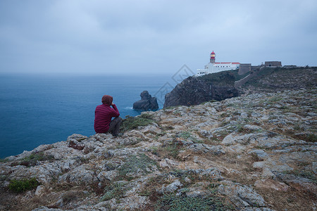 坐在悬崖上的人与圣文森特灯塔风景葡萄牙萨格里斯图片