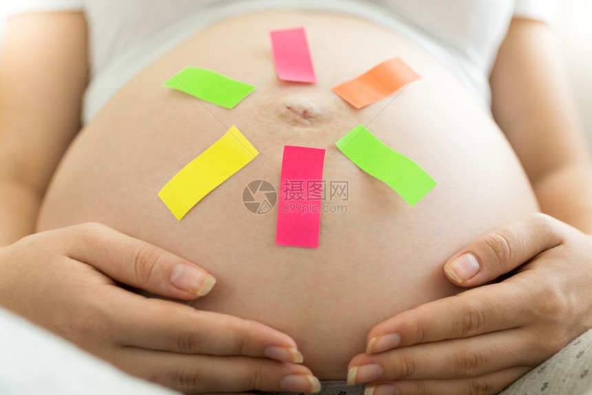 肚子上贴有备忘标签的年轻孕妇图片