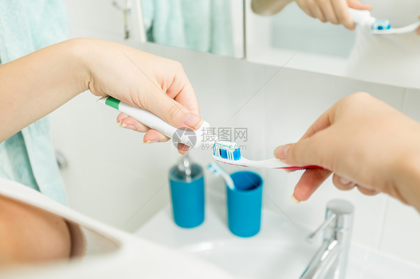 女士在浴室的杯子上用牙膏刷图片
