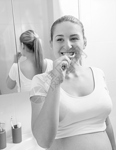 年轻孕妇在浴室刷牙的单色肖像图片