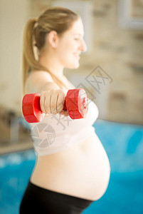 年轻孕妇在健身房用哑铃锻炼图片