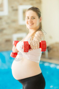 在健身房举哑铃的孕妇图片