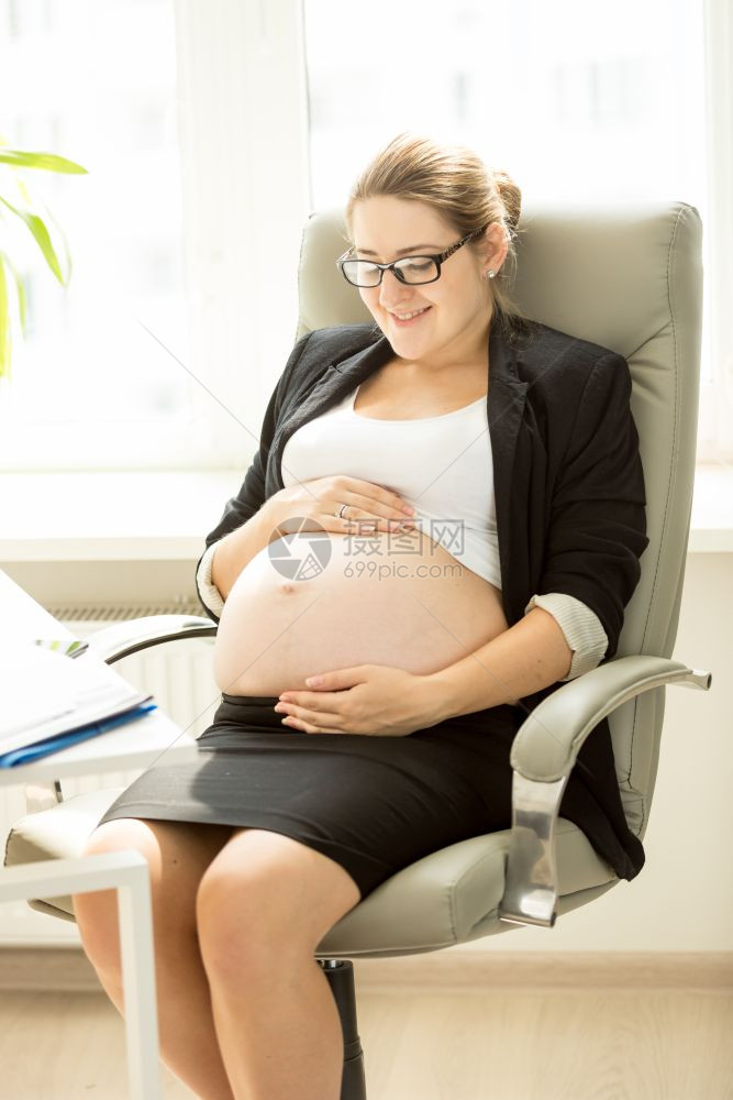 微笑的孕妇在办公室坐轮椅上摆姿势图片