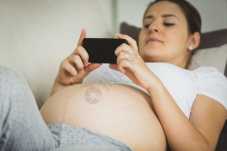 孕妇在智能手机上打信息图片