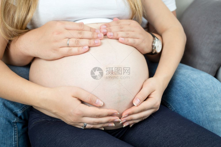 年轻怀孕夫妇用手摸着大肚子图片