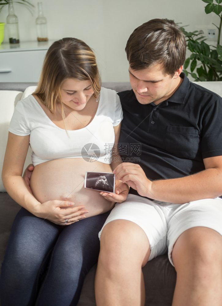 幸福的一对孕妇看着超声波婴儿扫描图片