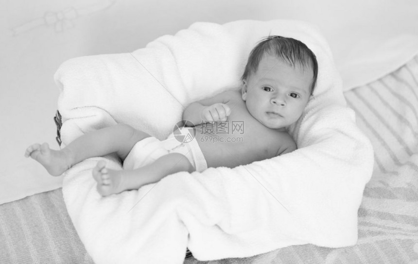 坐在大垫子上的可爱小男孩单色照片图片