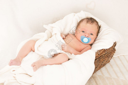 新生婴儿男孩躺在被毯子覆盖的旧阴道篮子里图片