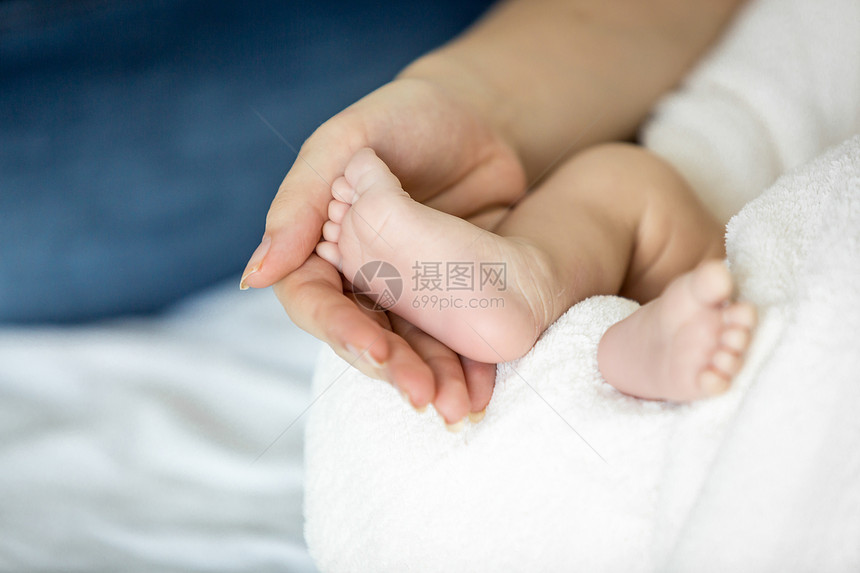 母亲将新生婴儿脚抱在床上的近视图像图片