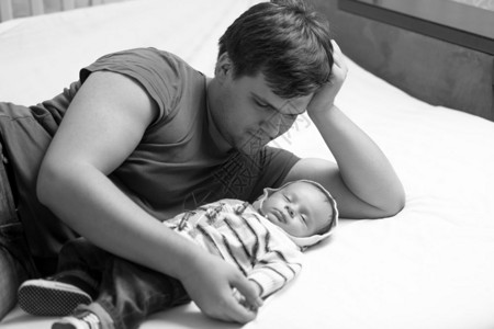 年轻父亲躺在新生儿身边的黑白年轻父亲肖像图片