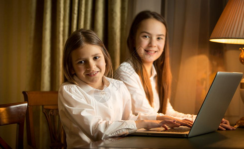 两个女学生晚上在笔记本电脑做家庭作业图片