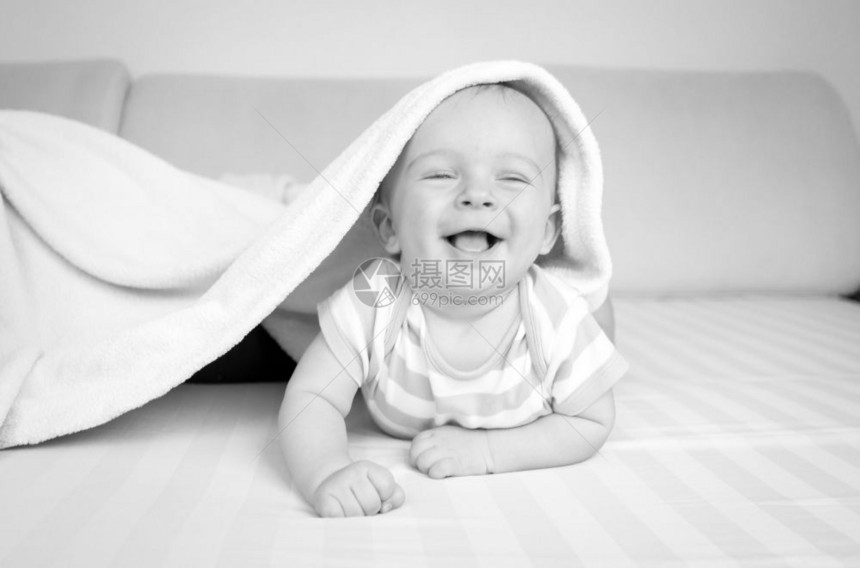 躺在毯子下床上的可爱小男孩黑白画像图片