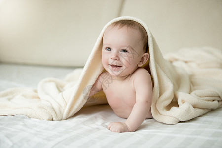 令人惊讶的婴儿男孩肖像躺在床上的毯子下躺在图片